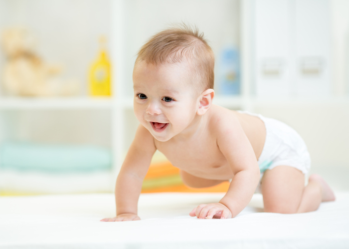 baby boy weared diaper crawling on bed at nursery
