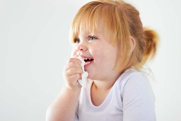 A cute baby girl laughing while holding a tissue