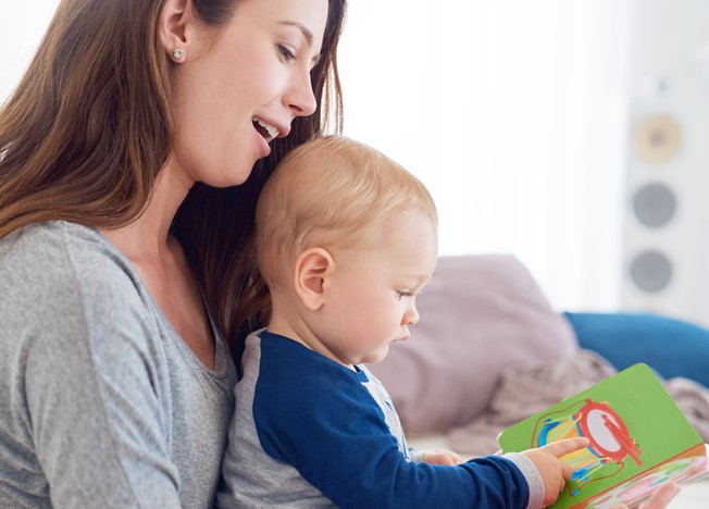 Cropped shot of a mother reading a book to her baby boy at home