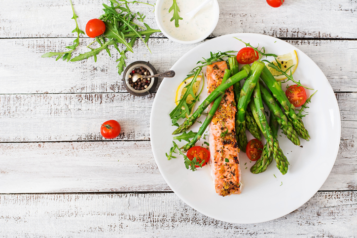 Baked salmon garnished with asparagus and tomatoes with herbs. Top view