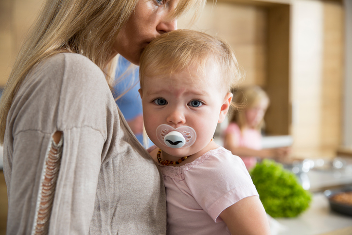Portrait of female toddler in mothers arms in kitchen